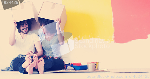 Image of young multiethnic couple playing with cardboard boxes