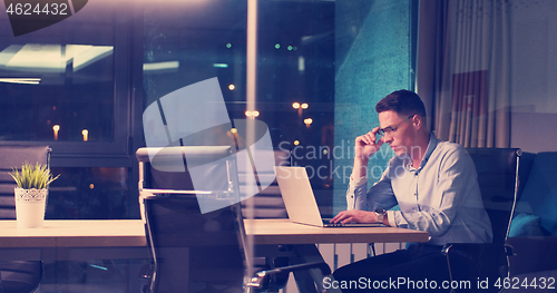 Image of man working on laptop in dark office