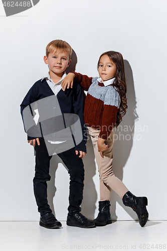 Image of The portrait of cute little boy and girl in stylish jeans clothes looking at camera at studio