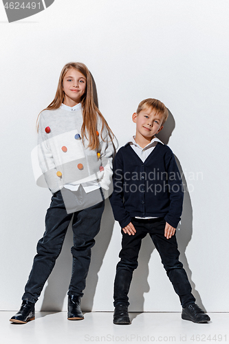 Image of The portrait of cute little boy and girl in stylish jeans clothes looking at camera at studio