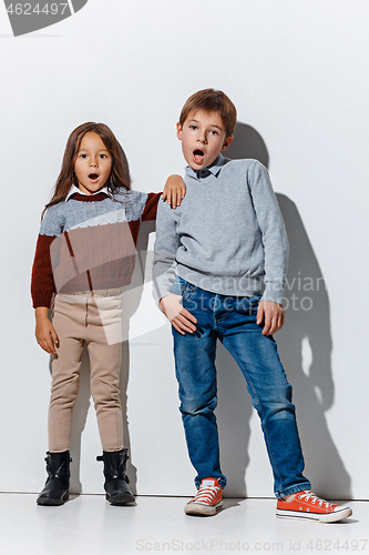 Image of The portrait of cute little boy and girl in stylish jeans clothes looking at camera at studio