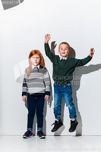 Image of The portrait of cute little boy and girl in stylish jeans clothes looking at camera at studio