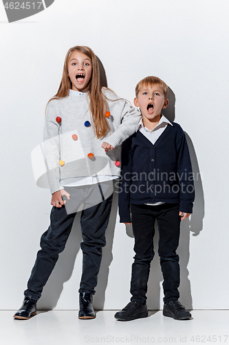 Image of The portrait of cute little boy and girl in stylish jeans clothes looking at camera at studio