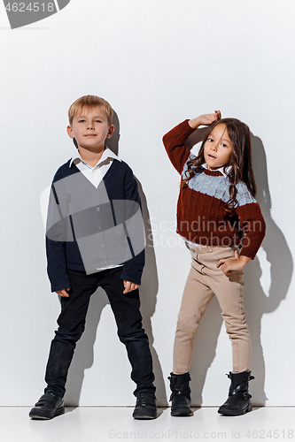 Image of The portrait of cute little boy and girl in stylish jeans clothes looking at camera at studio