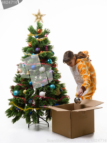 Image of Girl puts Christmas decorations in a storage box