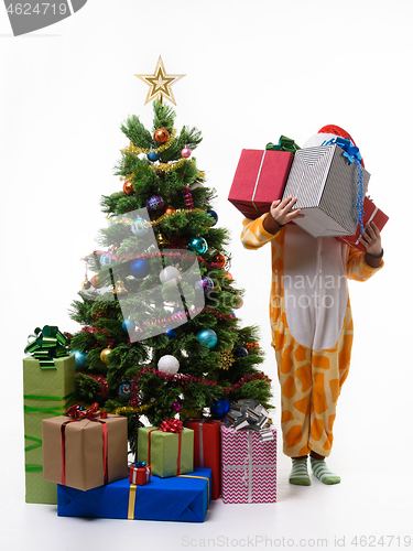 Image of Girl holding a bunch of gifts standing by the New Year tree