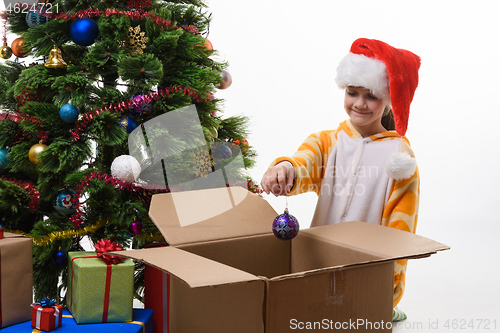 Image of Girl pulls Christmas ball out of the box