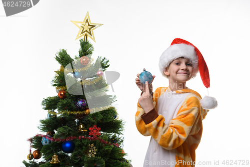 Image of The girl at the Christmas tree shows a Christmas toy
