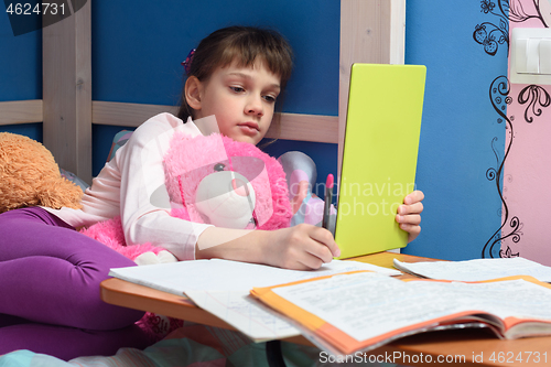 Image of Girl in the evening does homework at home using a tablet computer.