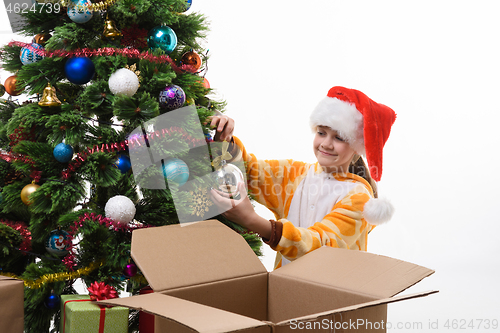 Image of Girl hangs a Christmas ball on the Christmas tree