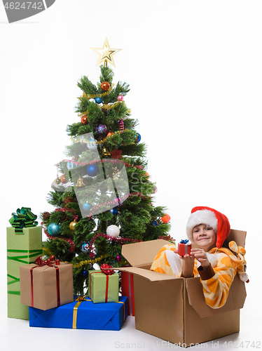 Image of Girl with a small gift sits in a sick box near the Christmas tree