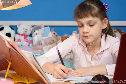 Image of The girl at the table at home does school lessons.