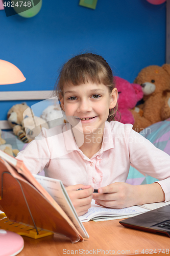 Image of Smiling girl is doing homework at home.