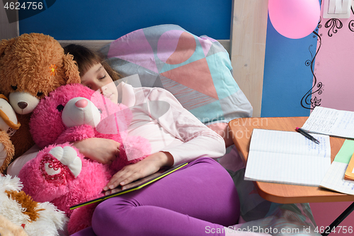 Image of Girl fell asleep in bed studying remotely and doing homework