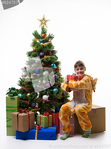 Image of Girl hugs a New Year\'s gift while sitting on a large storage box