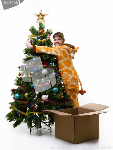 Image of Girl hugs Christmas tree and looks in the frame