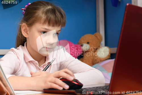 Image of The girl is remotely studying at home, working in a laptop