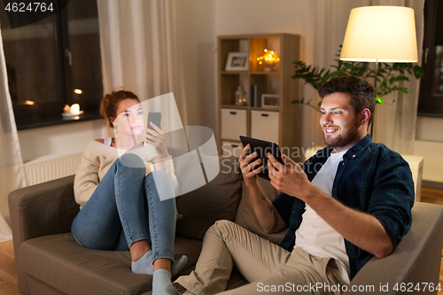 Image of couple with tablet computer and smartphone at home