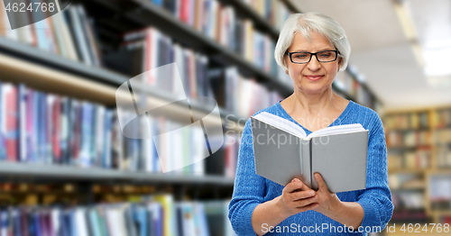 Image of senior woman in glasses reading book at library