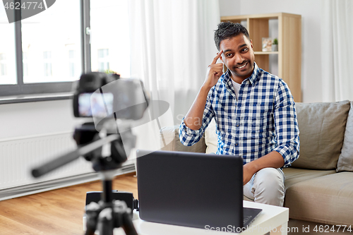 Image of male blogger with camera videoblogging at home