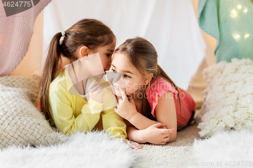 Image of happy girls lying in kids tent and talking at home