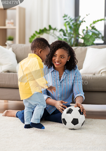 Image of mother and baby playing with soccer ball at home
