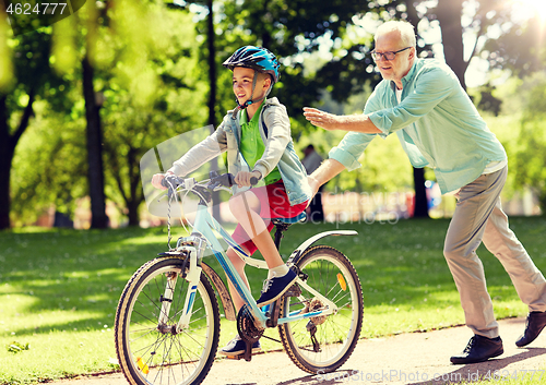 Image of grandfather and boy with bicycle at summer park