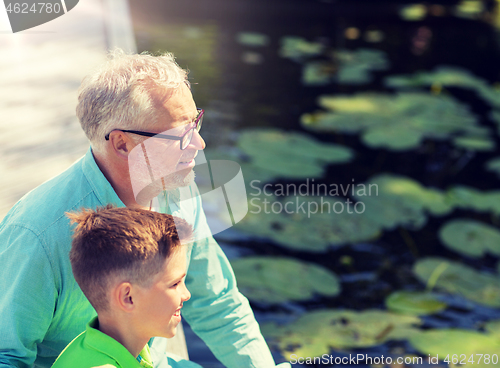 Image of grandfather and grandson sitting on river berth