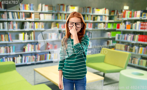 Image of red haired student girl in glasses at library