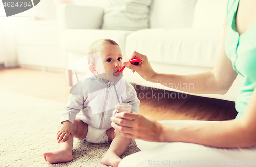 Image of mother with spoon feeding little baby at home