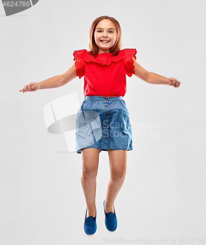 Image of happy smiling girl in red shirt and skirt jumping