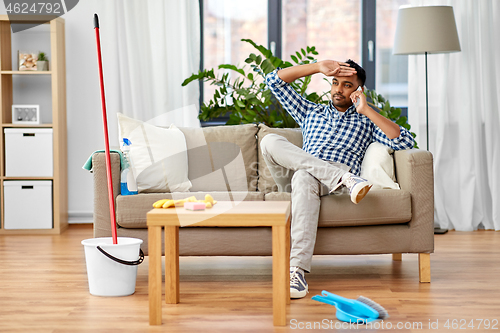 Image of man calling on smartphone after cleaning home