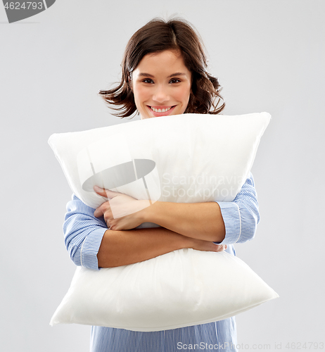 Image of happy young woman in pajama hugging pillow