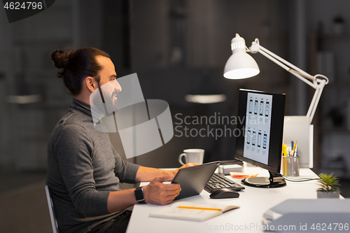 Image of creative man with computer working at night office