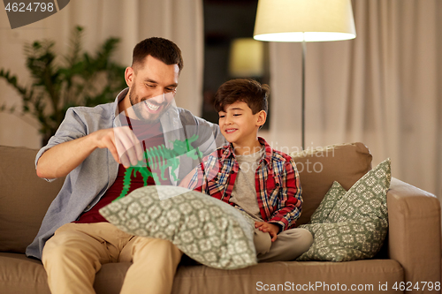 Image of father and son playing with toy dinosaur at home