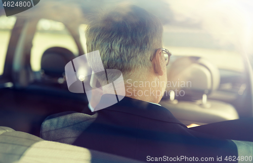 Image of senior businessman calling on smartphone in car