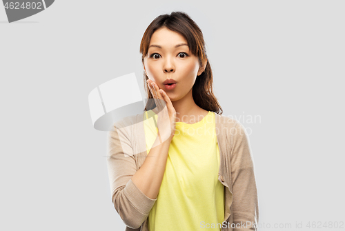 Image of surprised asian woman over grey background