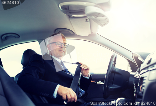 Image of senior businessman fastening car seat belt