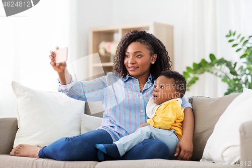 Image of african mother with baby son taking selfie at home