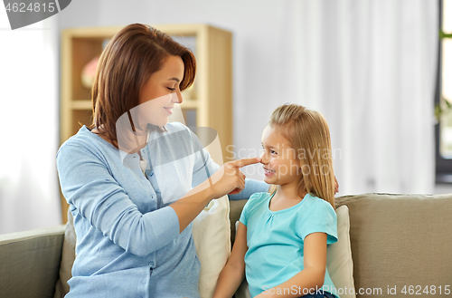 Image of mother and daughter sitting on sofa at home