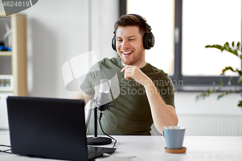 Image of man with laptop and microphone at home office