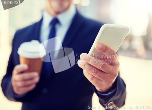 Image of senior businessman with smartphone and coffee