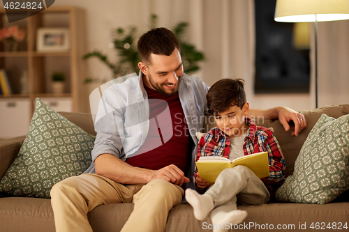 Image of happy father and son reading book sofa at home