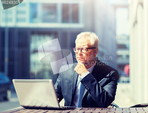 Image of senior businessman with laptop at city street cafe