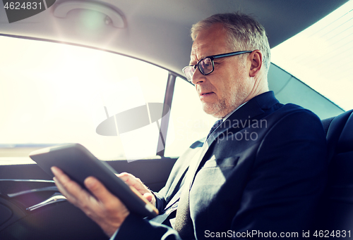 Image of senior businessman with tablet pc driving in car