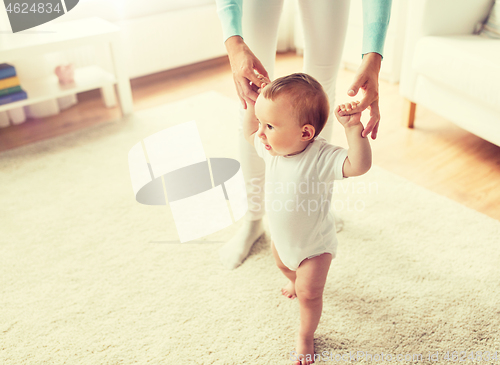 Image of happy baby learning to walk with mother help