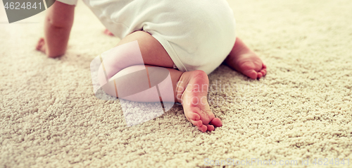 Image of little baby in diaper crawling on floor at home