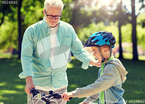 Image of grandfather and boy with bicycle at summer park