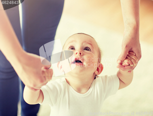 Image of happy baby learning to walk with mother help