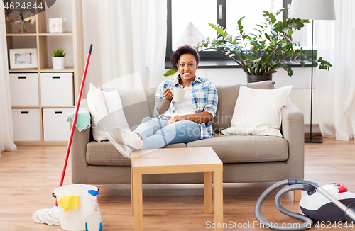 Image of woman drinking coffee or tea after cleaning home